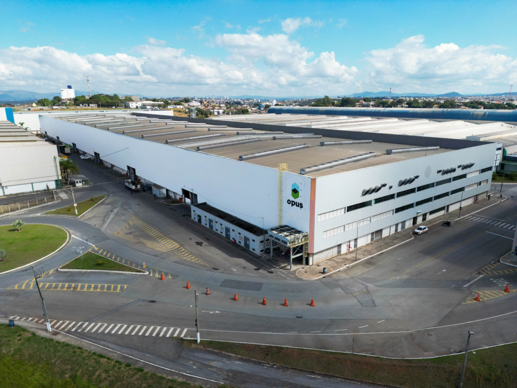 Visão aérea do complexo industrial e sede da Opus Construtech em Betim, Minas Gerais. A vasta estrutura abriga a fábrica de construção modular e os escritórios corporativos da empresa.