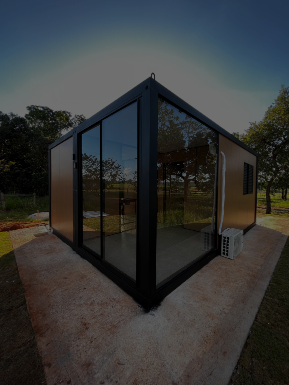 Módulo comercial moderno. A estrutura possui painéis de fachada amadeirados e duas paredes contíguas com grandes fechamentos de vidro e porta de correr em caixilharia escura, sobre base de concreto.