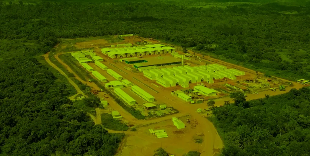 Alojamento modular de grande. A imagem de drone destaca a extensa vila de módulos padronizados da Opus sobre um terreno de terra cercado por vegetação densa.