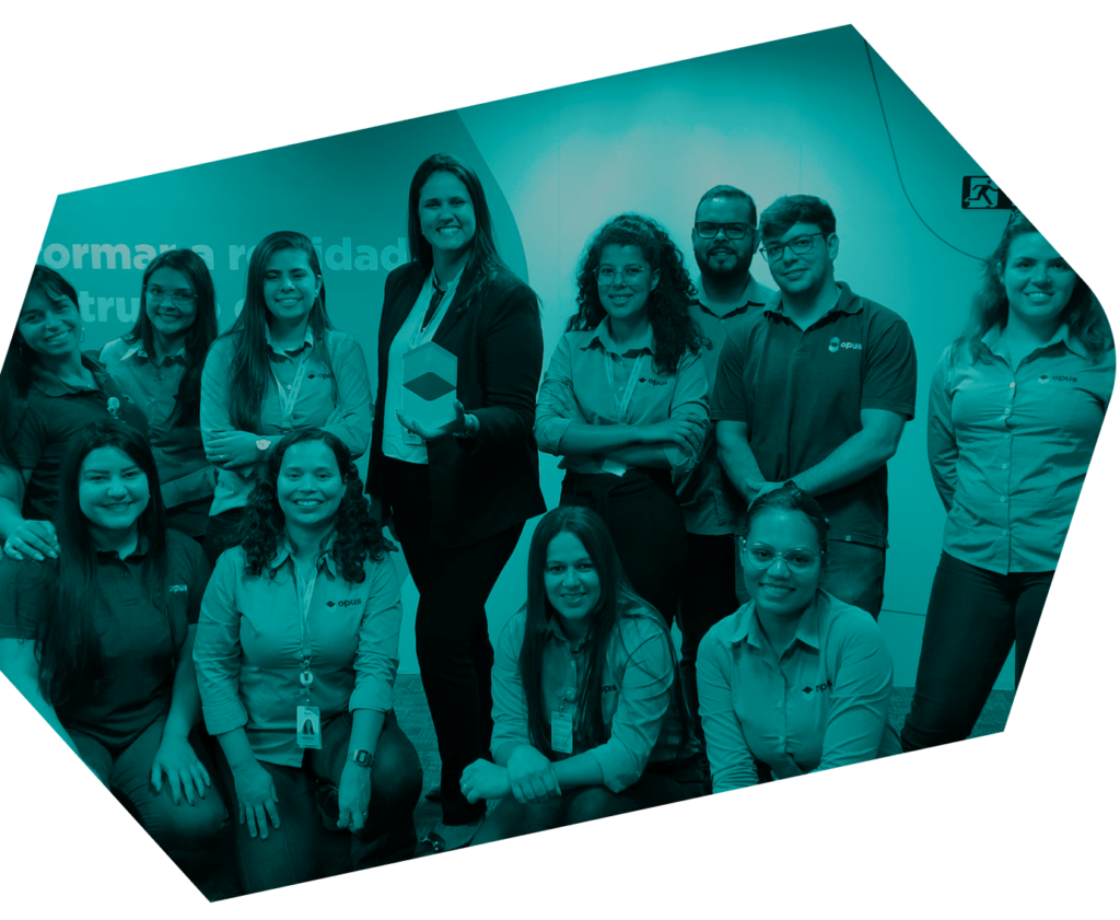 Fotografia de um grupo de cerca de 12 funcionários. A maioria deles vestem camisas com a marca Opus e estão sorrindo.