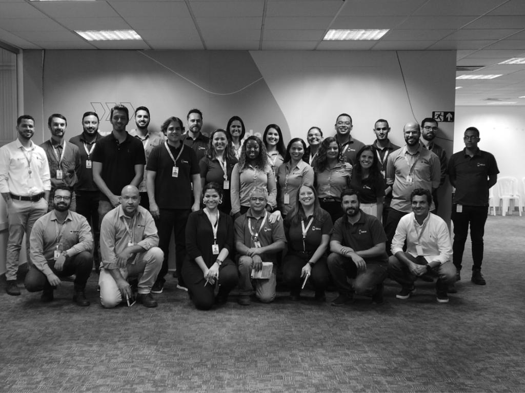 Fotografia em preto e branco da equipe de profissionais e do CEO da Opus Construtech reunidos no escritório corporativo da empresa.