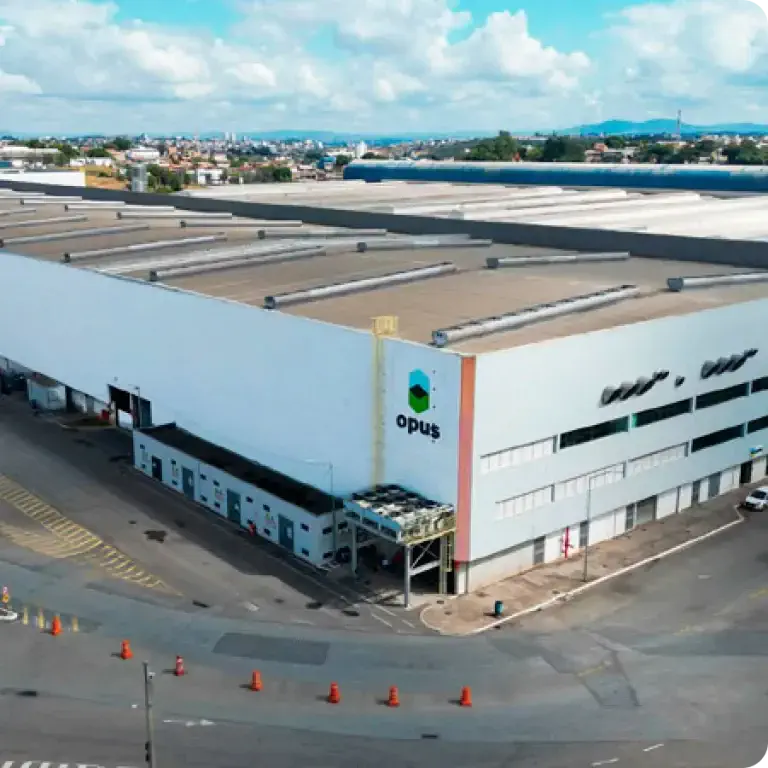 Visão aérea do complexo industrial e sede da Opus Construtech em Betim, Minas Gerais. A vasta estrutura abriga a fábrica de construção modular e os escritórios corporativos da empresa.